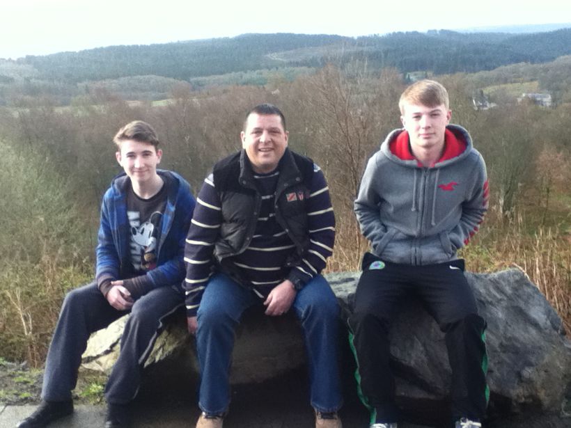 Brian sits on a rock with his two sons