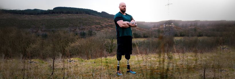 Double amputee Bruce is standing in a field showing strength on