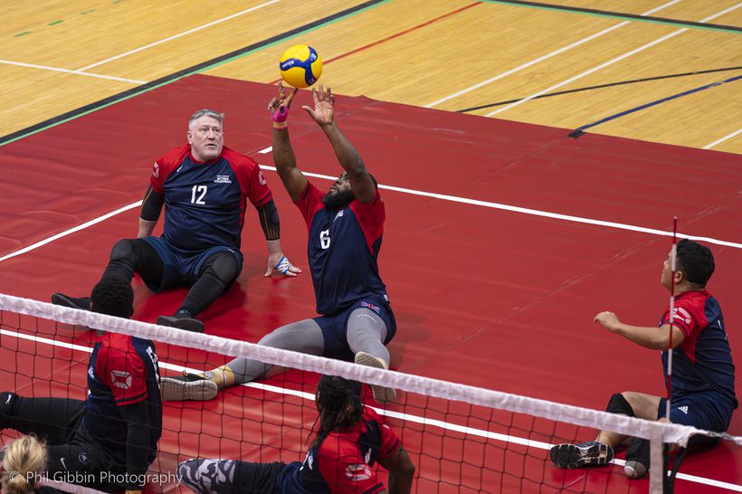 A player making a shot in a sitting volleyball game.