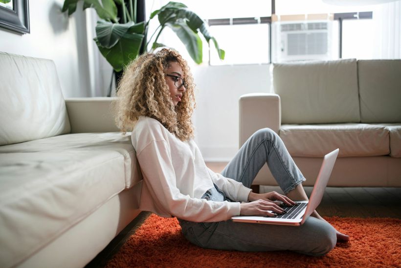 a woman using a laptop computer sat on the floor of her lounge