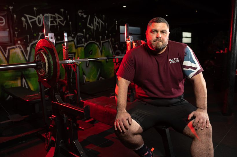 Darren sits on a weights bench at the gym he works at