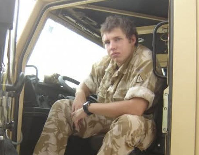 Soldier sitting in the cab of an army vehicle looking to camera