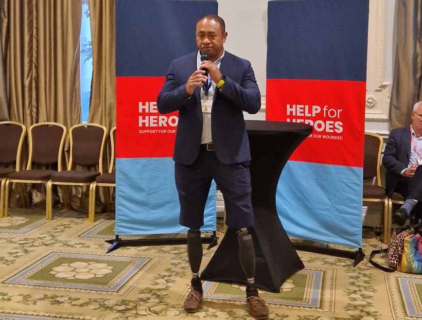 Derek Derenalagi standing in front of Help for Heroes banners