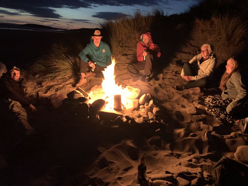 Walkers sit around a night-time campfire