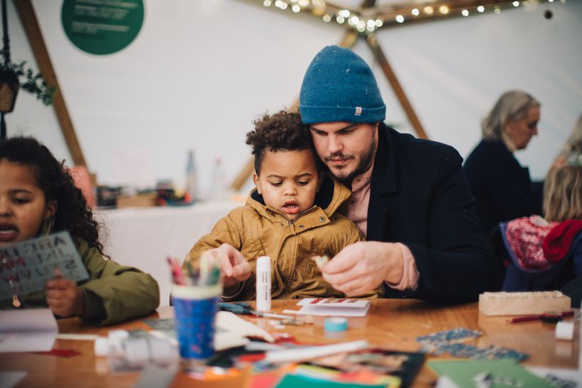 A parent and a child sit closely together Xmas crafting