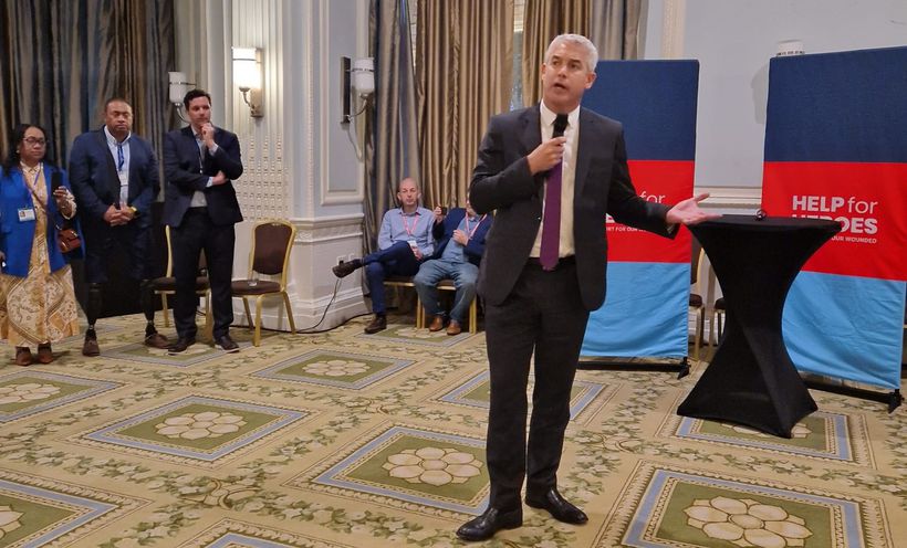 Steve Barclay with microphone in front of banner