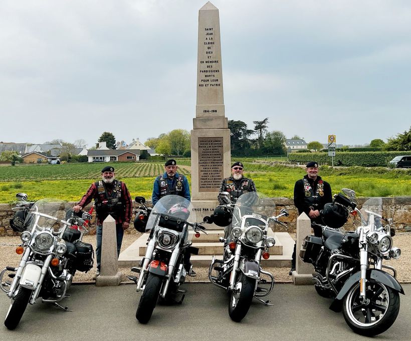 Four veteran bikers posing in front of a war memorial