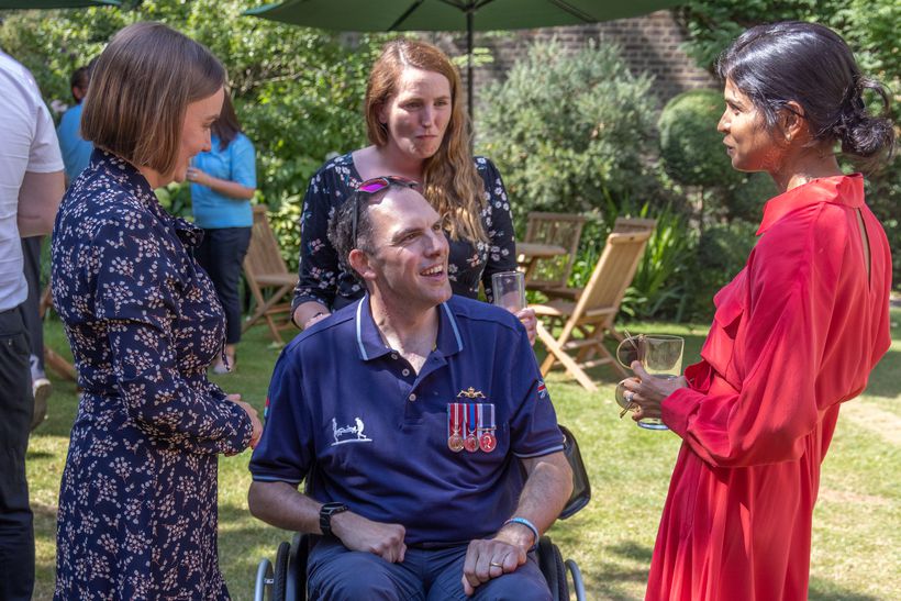 Ryan Thomas sitting in garden in blue shirt with three women