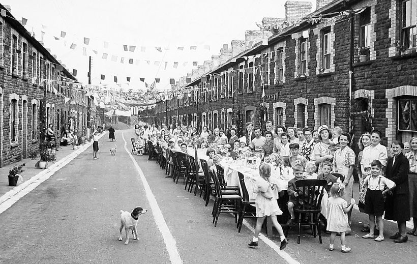 A streety party with a long table and people sat on chairs