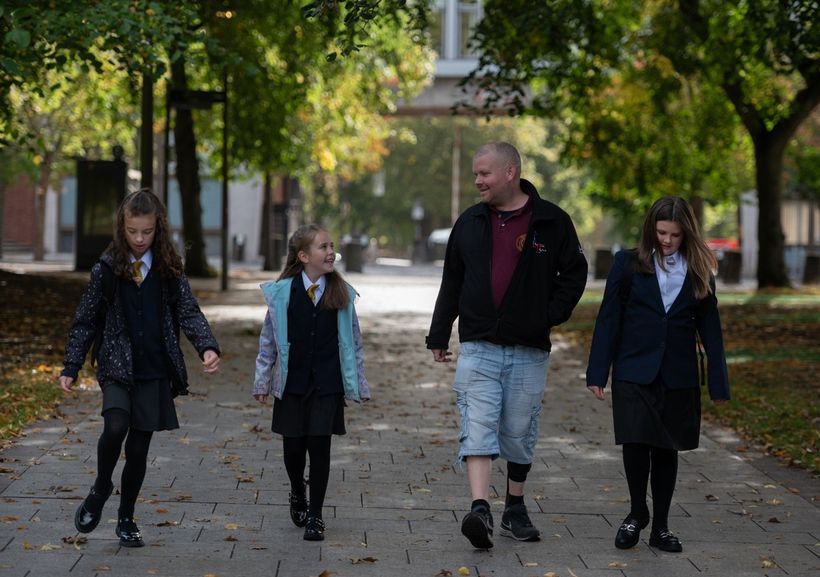 Photo shows Tony walking with his three daughters.