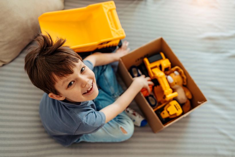 A child fills a cardboard box with old toys