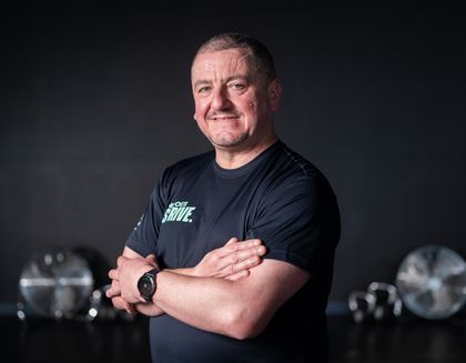 Andrew, the instructor is smiling, with his arms crossed - against a dark background.