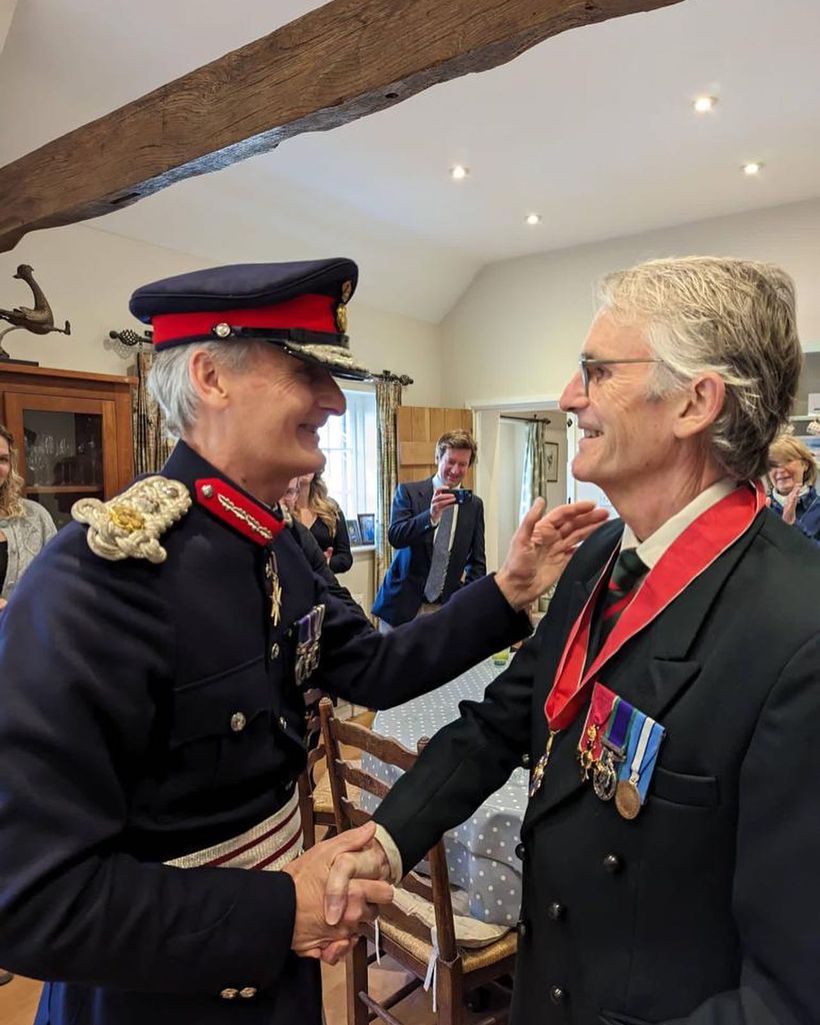 An image of Bryn Parry being appointed CBE by Nigel Atkinson.