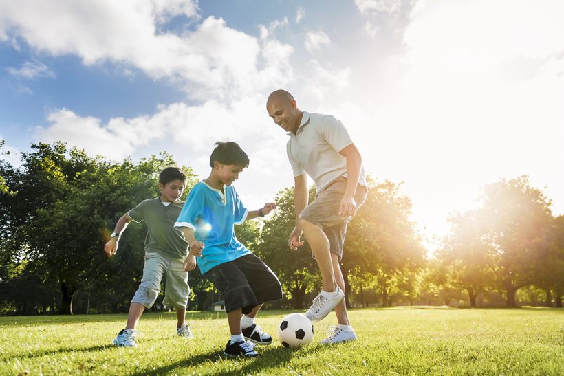 family playing football in a sunny field