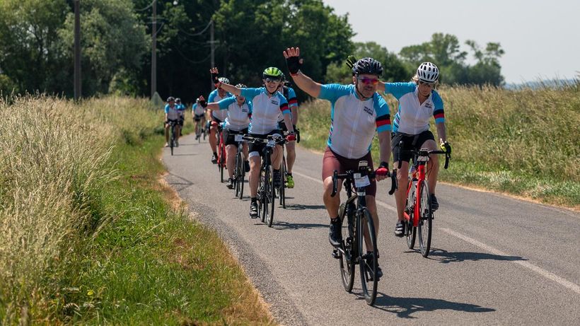 Group of cyclists smiling whilst riding in the sun
