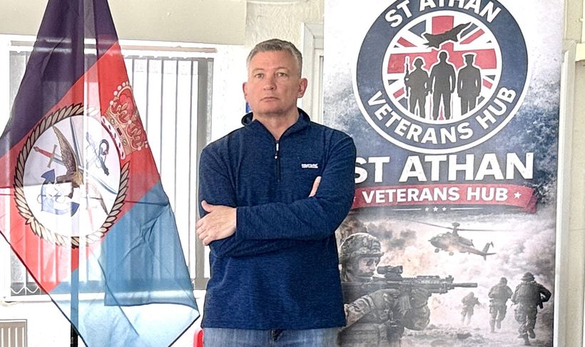 Image shows Derek in front of a St Athans banner