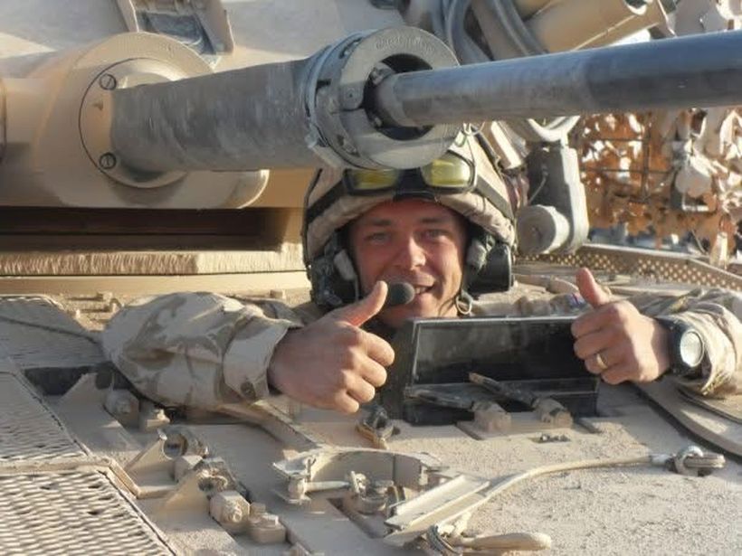 Dan Thomson wearing Army fatigues and sat in a tank