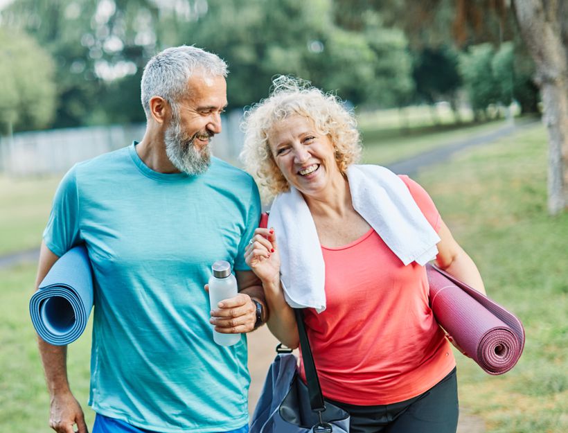Older couple walking together with yoga mats