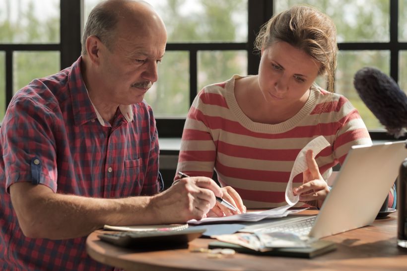 Daughter helping elderly father sort documents.