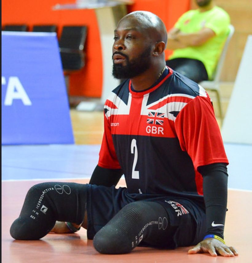 Corie sits on the court during a sitting volleyball match