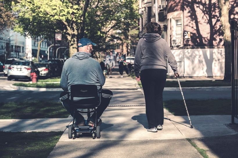 man and woman in street both using a mobility aid