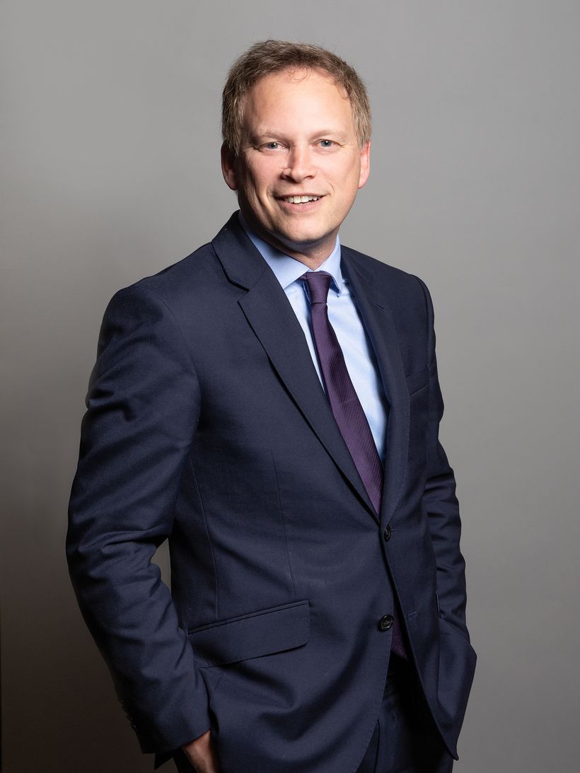 Man in dark suit faces camera